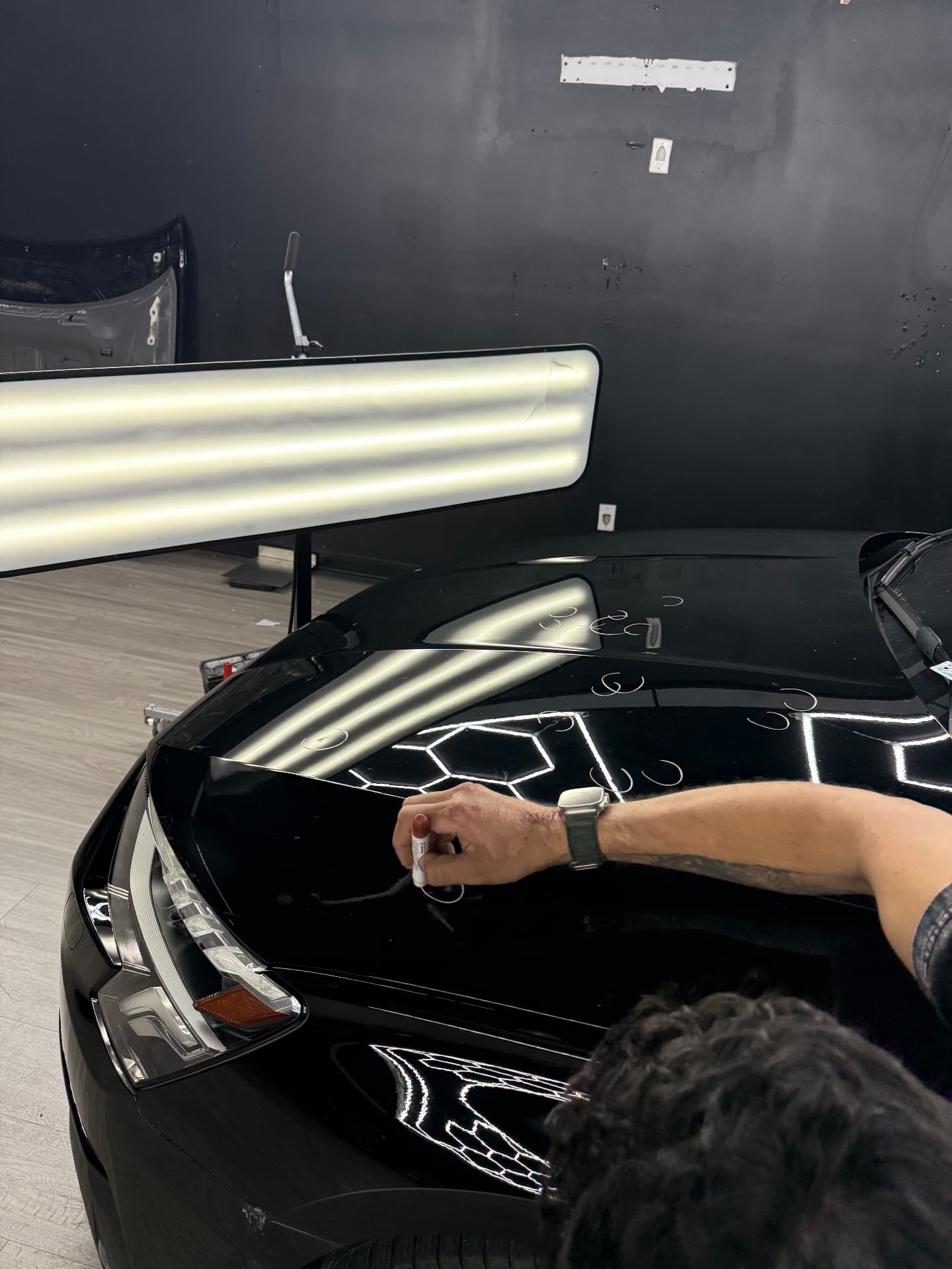 Close-up paintless dent repair work on a black vehicle panel